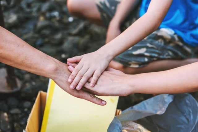 benefits-of-volunteering Hands joined in support during volunteering for students.