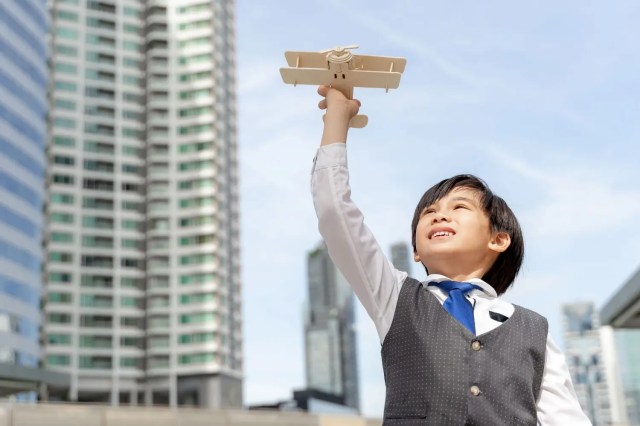 Boy holding a toy aeroplane, symbolising leadership skills for students.