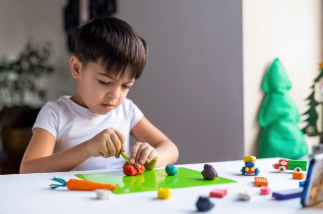 Child engaging in play-based learning by shaping colourful modelling clay