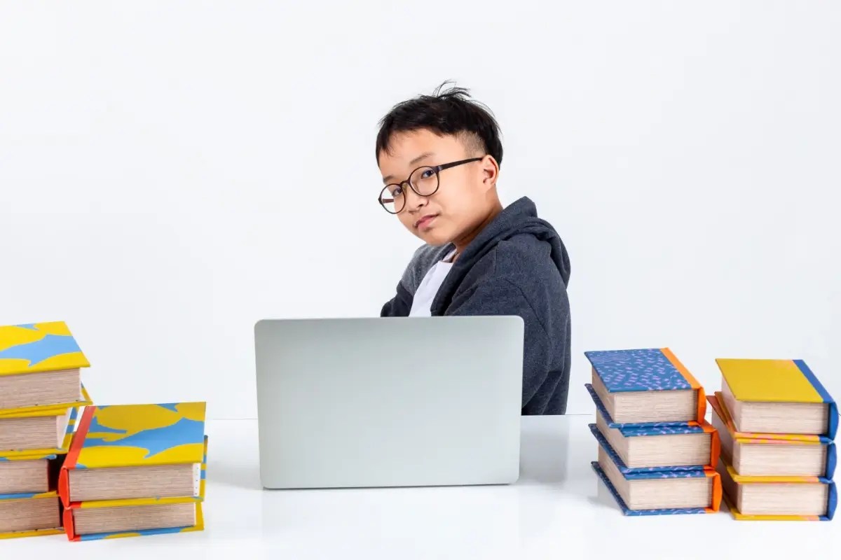 Student studying with books and a laptop, representing child self-esteem.