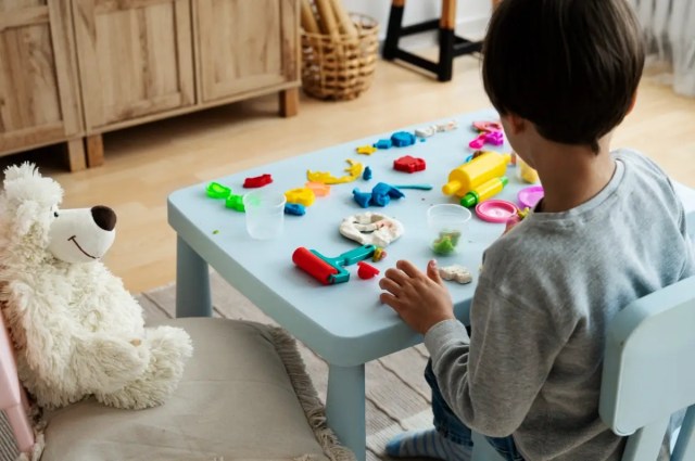 Child enjoying play-based learning with modelling clay and creative tools.
