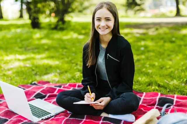 healthy-learning-envireonment Student wellbeing in a healthy learning environment with a smiling student studying outdoors.
