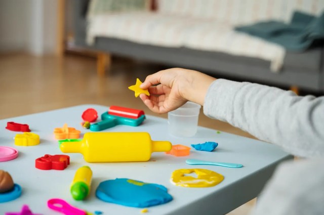 sensory-play-matters Child holding a playdough star during a sensory play activity with colourful tools and tactile materials.