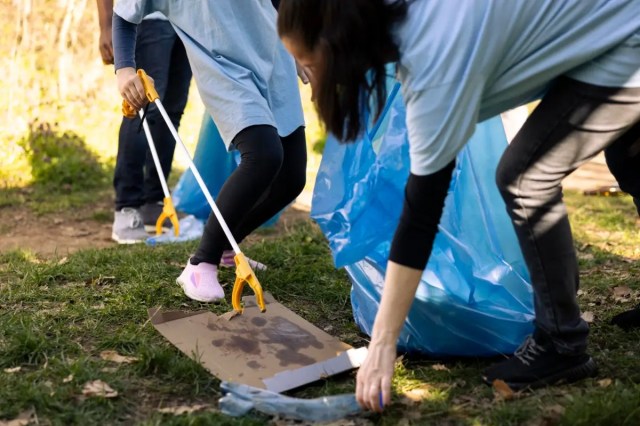 Students participating in service learning in schools by collecting litter during a community clean up.