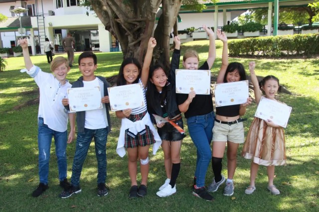 Smiling student outdoors balancing books on his head, symbolising resilience in a changing world.