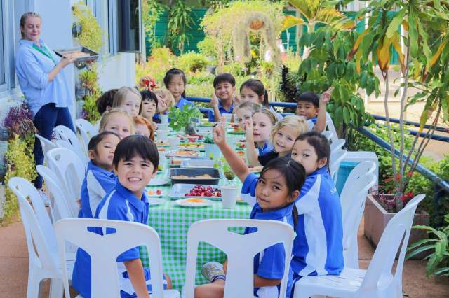 student-enjoying-lunch-together-outdoors Happy students enjoying lunch together outdoors in the school garden, surrounded by fresh food and greenery