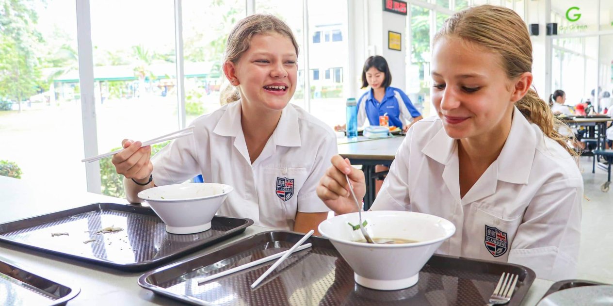 Happy students enjoying lunch and conversation in the international school canteen