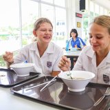 Happy students enjoying lunch and conversation in the international school canteen