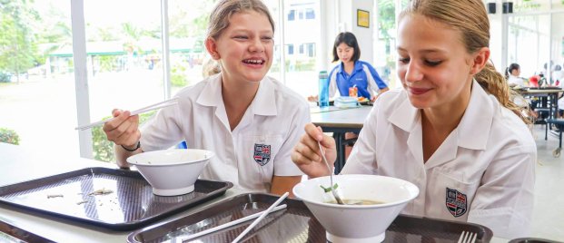Happy students enjoying lunch and conversation in the international school canteen