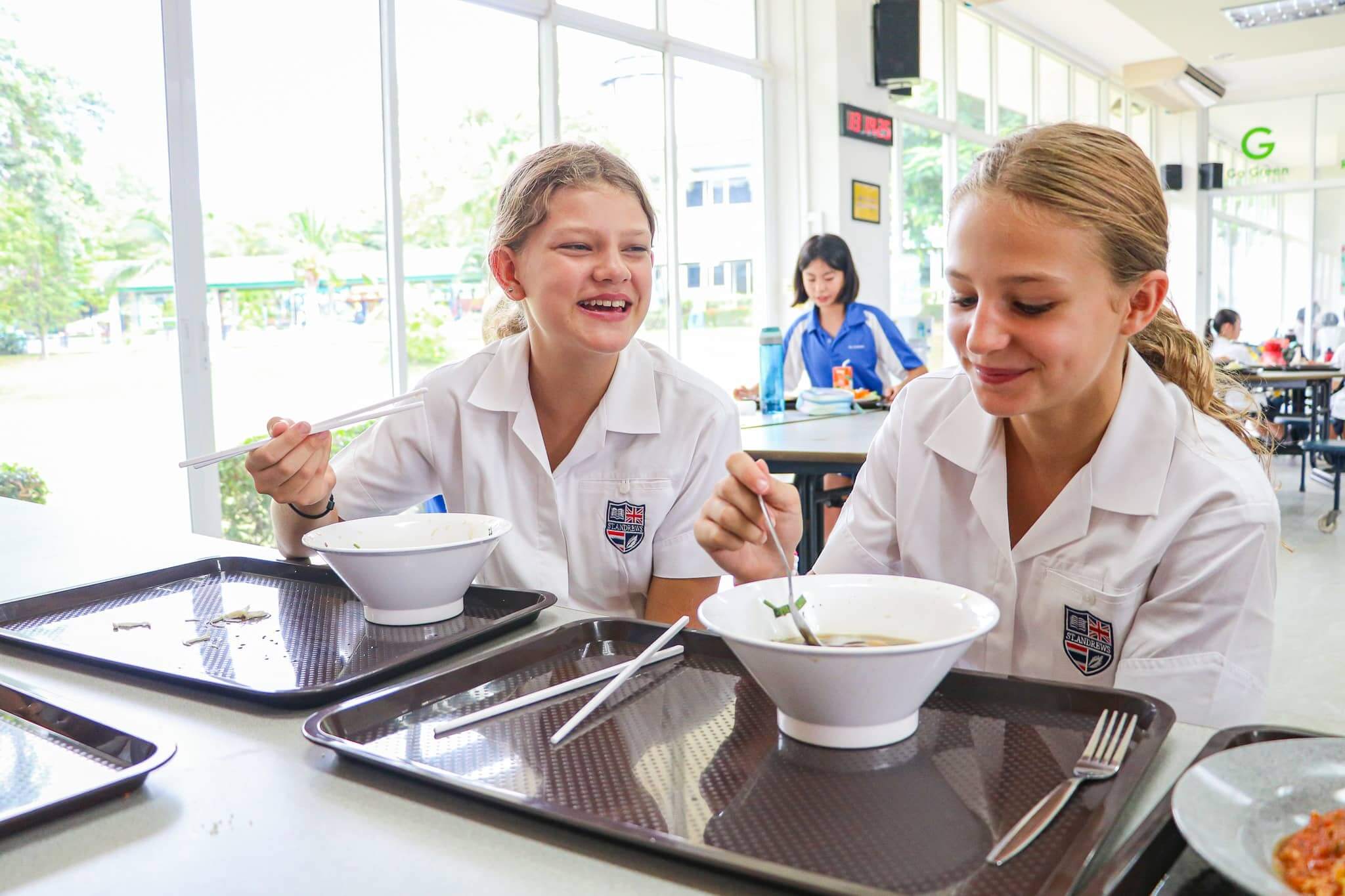 Happy students enjoying lunch and conversation in the international school canteen