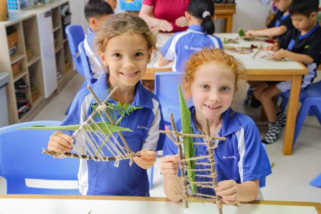 students-smiling-proudly-with eco-friendly Students smiling proudly with eco-friendly art made from natural and recycled materials at their eco school