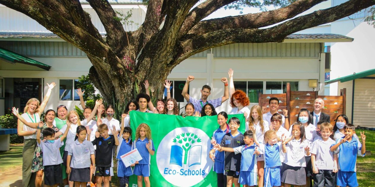 a group of students and teachers celebrating the school’s Green flag award for their eco-school