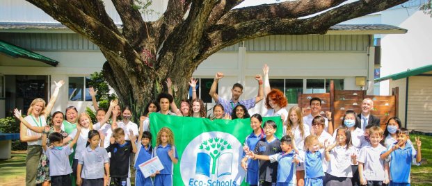 a group of students and teachers celebrating the school’s Green flag award for their eco-school