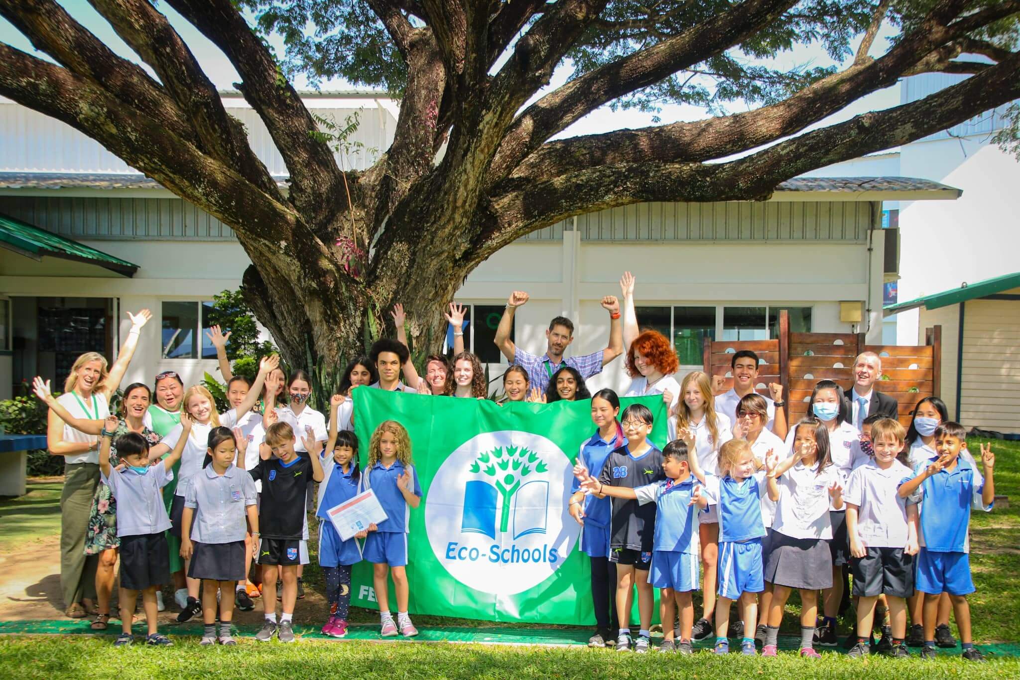 a group of students and teachers celebrating the school’s Green flag award for their eco-school