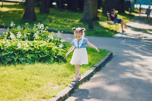 Young child walking along a grassy path surrounded by trees, illustrating the benefits of green spaces for students.