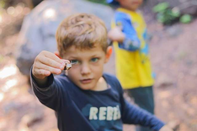 developing-curiosity Preschooler at St. Andrews Green Valley closely examines a tiny forest insect during outdoor learning, developing curiosity and real-world observation skills.