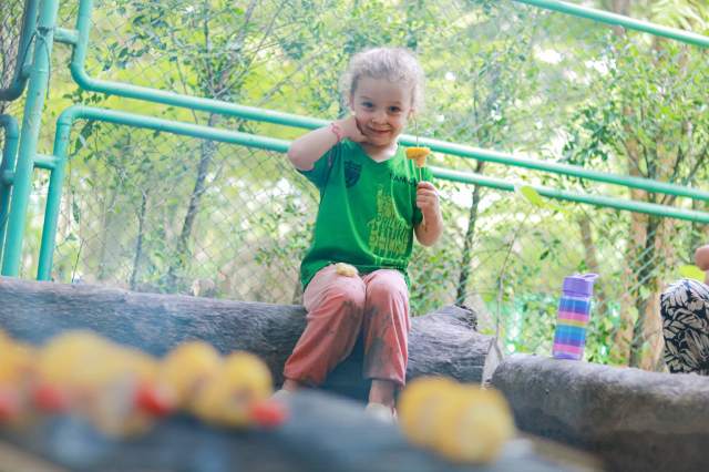 A Forest School student at St. Andrews Green Valley proudly enjoys roasted vegetables after outdoor cooking, building independence, problem-solving skills, and confidence through hands-on forest school experiences.