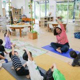 Teacher leads kids in fun stretching, showing how simple mental health activities for students boost focus and wellbeing.