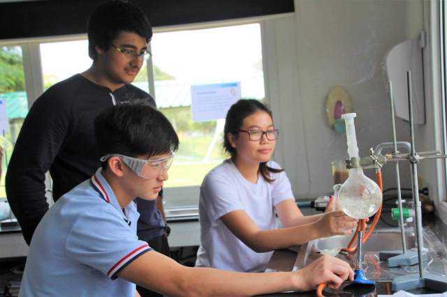 problem-solving IBDP students conduct a science experiment together, balancing teamwork, precision, and real-time problem-solving