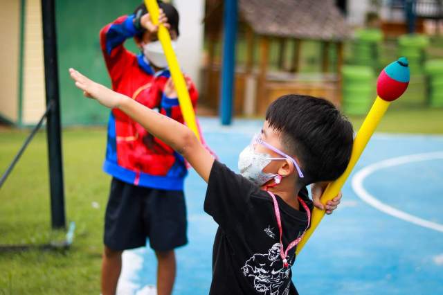 Young children engage in energetic outdoor play, showing confidence, focus, and early signs of interest through movement and imagination.