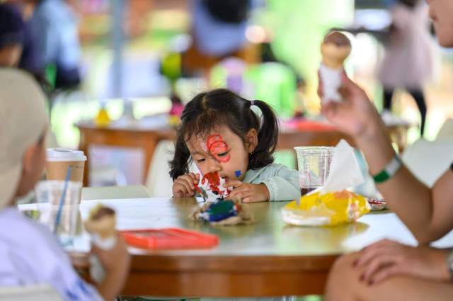 Young girl focuses intently on painting during a hands-on activity, expressing creativity and exploring her interests through open-ended materials.