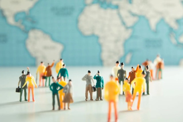 Miniature figures connected across a world map, illustrating the importance of becoming a global citizen.