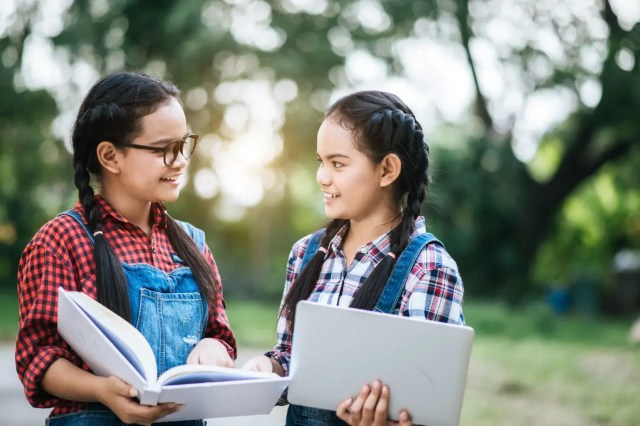 Two students studying together outdoors, reflecting sustainability in education.