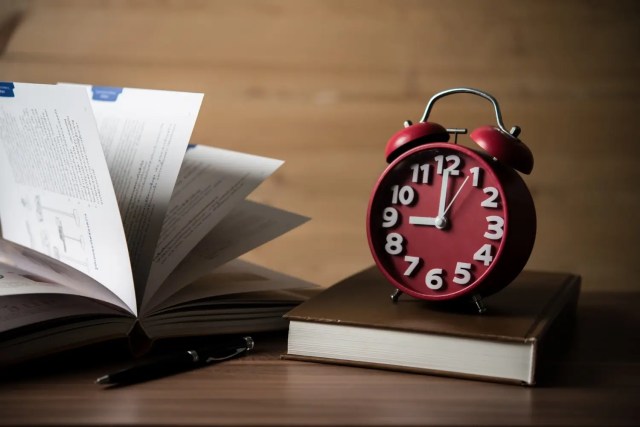 Books and alarm clock on study desk illustrating time management for students.
